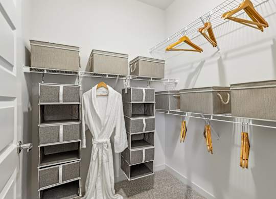 A walk in closet with a white robe hanging on a rail.