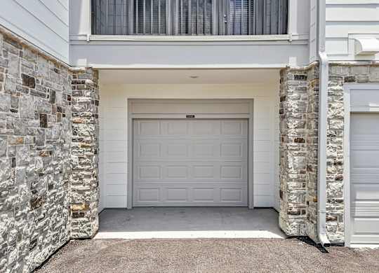 A white garage door is flanked by two stone pillars.