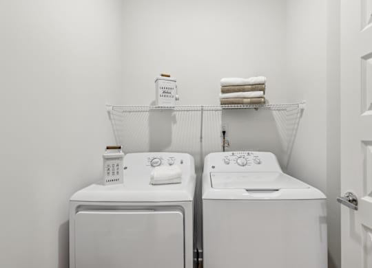 A white laundry room with two washing machines and a towel rack.