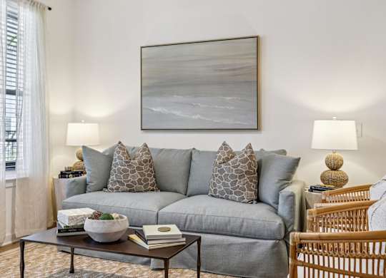 A living room with a grey couch, a coffee table, and a painting on the wall.