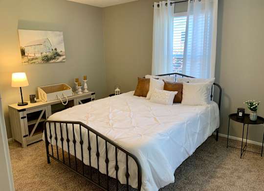 Bedroom with window and carpet at The Avery at Auburn Apartments in Auburn, AL