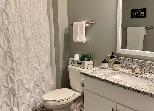 bathroom with wood flooring and granite countertops at The Avery at Auburn Apartments in Auburn, AL