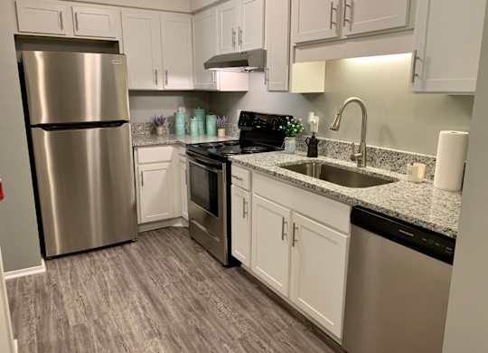 Kitchen with stainless steel appliances, wood style flooring, and gooseneck faucet at The Avery at Auburn Apartments in Auburn, AL