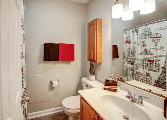 A bathroom with a toilet, sink, and a mirror.