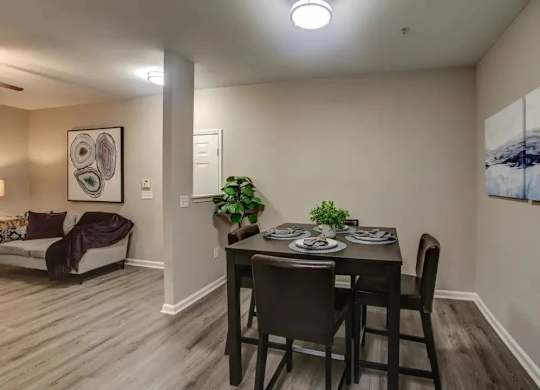 A dining room with a table set for two and a couch with a throw blanket.