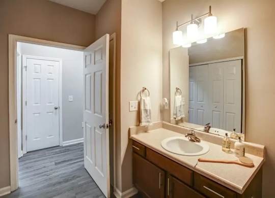 A bathroom with a white door and a brown vanity.