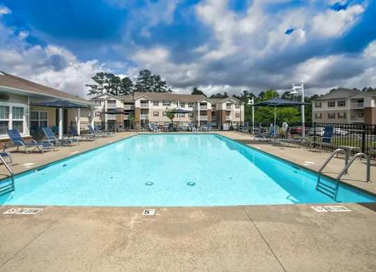 A large swimming pool in a residential area with a cloudy sky.