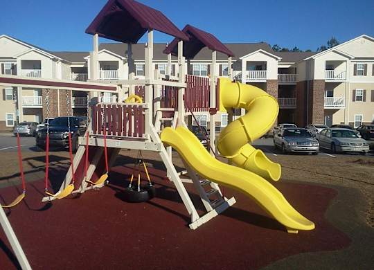 A yellow slide in a playground with a red roof.