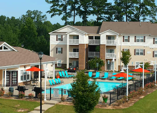 A large apartment complex with a pool and a fence.