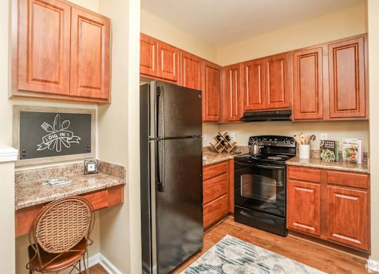 A kitchen with wooden cabinets and a black fridge.