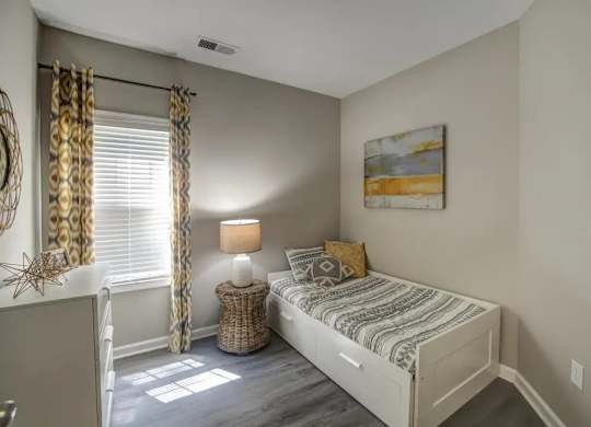 A bedroom with a bed, nightstand, and window.