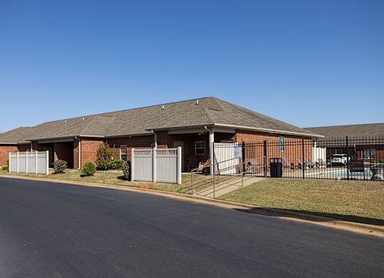 A long building with a grey roof and a fence in front of it.