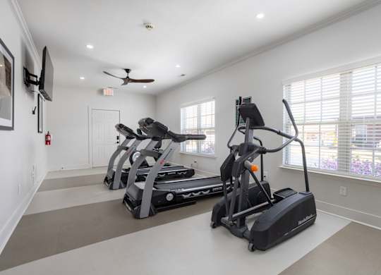 A spacious room with a treadmill and elliptical trainer.