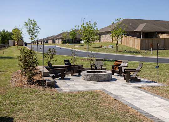 A park with a fire pit and benches.