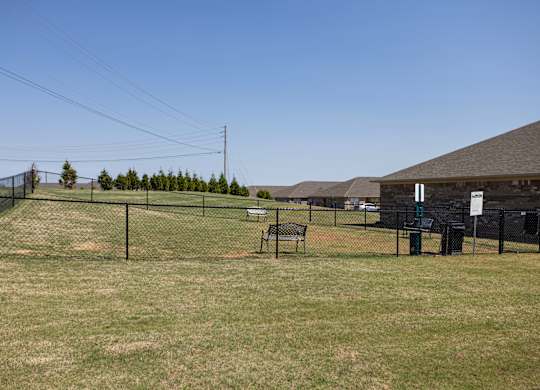 A grassy field with a fence and a bench.
