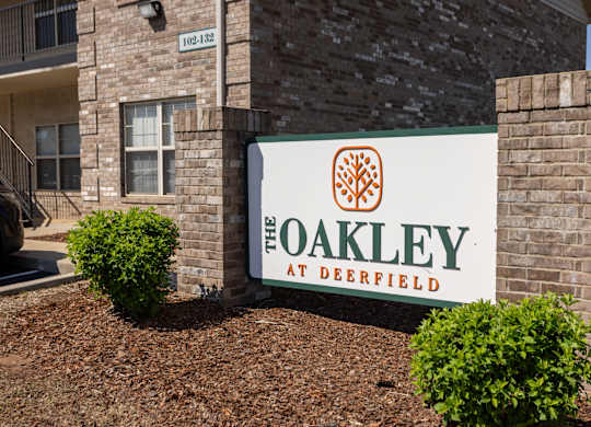 A sign for The Oakley at Deerfield is displayed in front of a building.