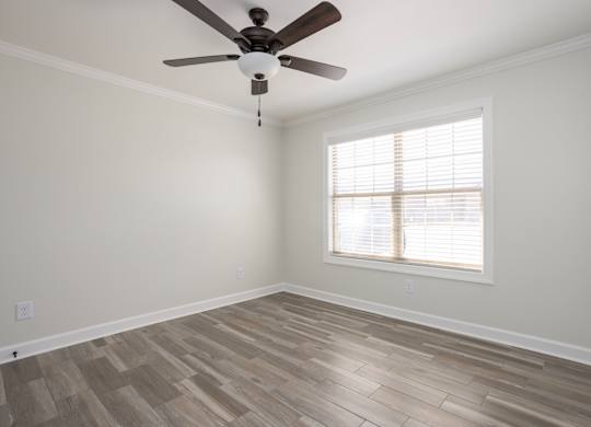 A room with a ceiling fan and a window with blinds.