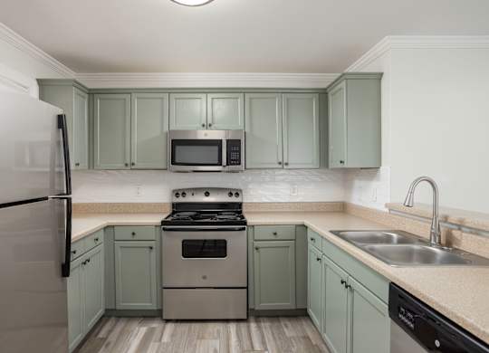 A kitchen with a stove, refrigerator, and microwave.