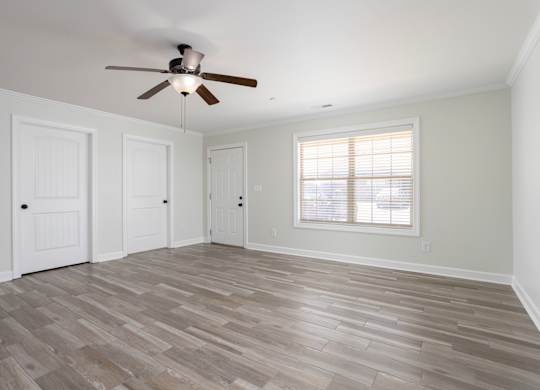 A room with a ceiling fan and wooden flooring.