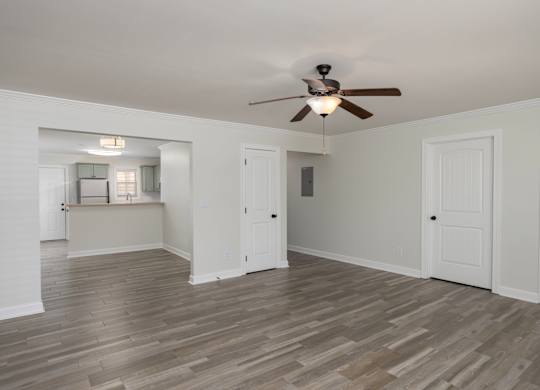 A room with a ceiling fan and wooden flooring.