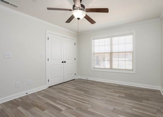 A room with a ceiling fan and a window with blinds.