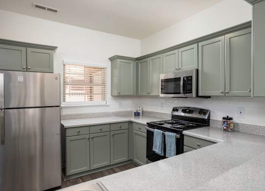 A kitchen with a refrigerator, microwave, oven, and cabinets.