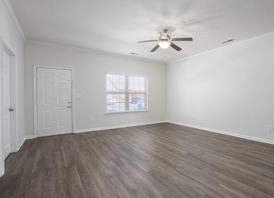 A room with a ceiling fan and wooden flooring.