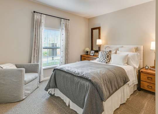 A bedroom with a large bed and a chair.