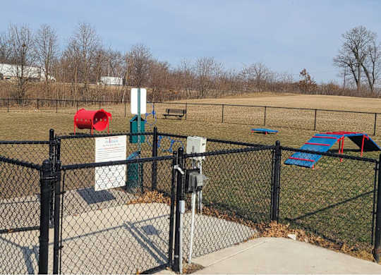 a dog park with a chain link fence and playground equipment t The Pomenade at Founders Square Apartments in Portage, IN