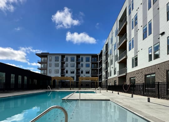 A sparkling swimming pool with wide, shallow entry steps in front of the Fitzroy Apartments in Birmingham, Alabama.