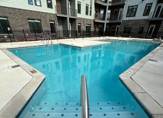 A sparkling swimming pool with wide, shallow entry steps in front of the Fitzroy Apartments in Birmingham, Alabama.