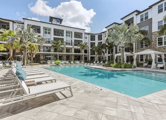 a swimming pool with lounge chairs and a building in the background