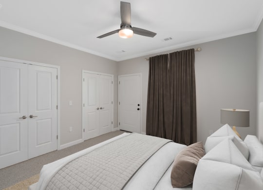 a bedroom with a large bed and a ceiling fan at The Cottages at Foley Farms apartments in Foley, AL
