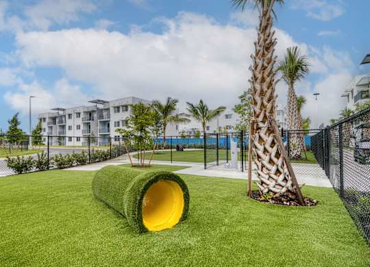 A playground with a yellow tunnel and a palm tree.