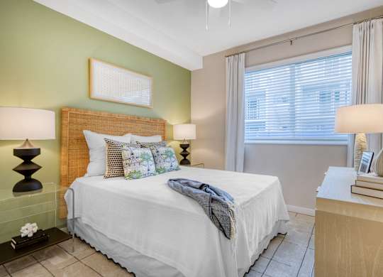 A bedroom with a white bed and a green wall.