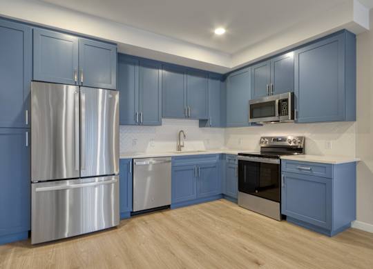 A kitchen with blue cabinets and stainless steel appliances.