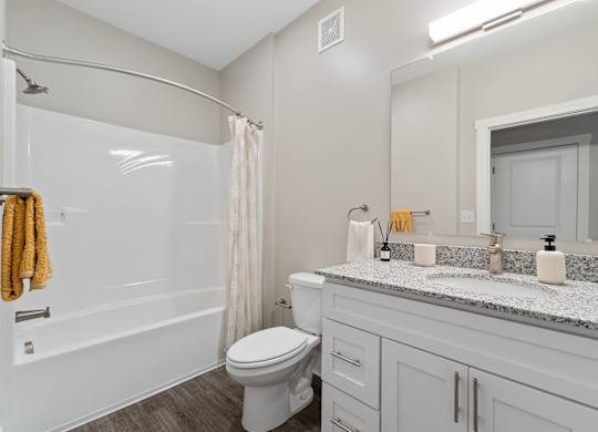 A white toilet sits in a bathroom with a marble counter top.