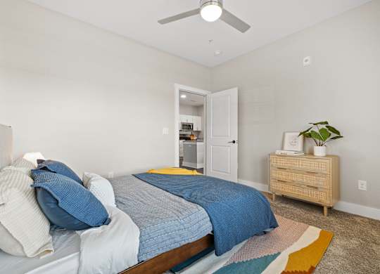 A bedroom with a bed, a dresser, and a ceiling fan.