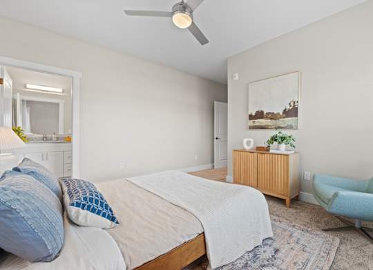 A bedroom with a bed, a chair, and a painting on the wall.
