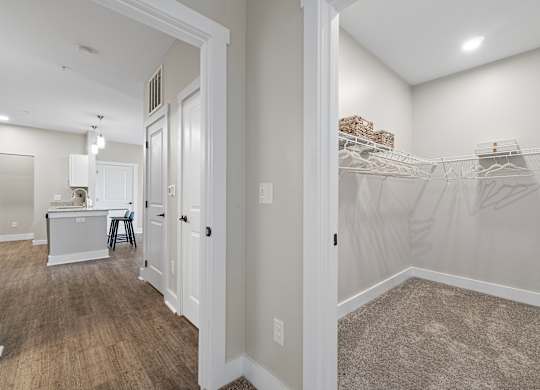 A white closet with clothes hanging on the rack.