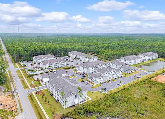 A bird's eye view of a large residential complex surrounded by a forest.