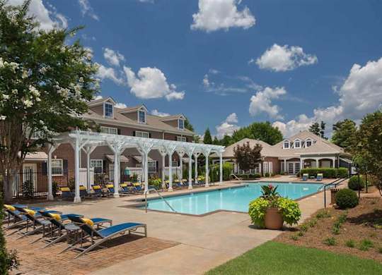 A pool area with sun loungers and a building in the background.