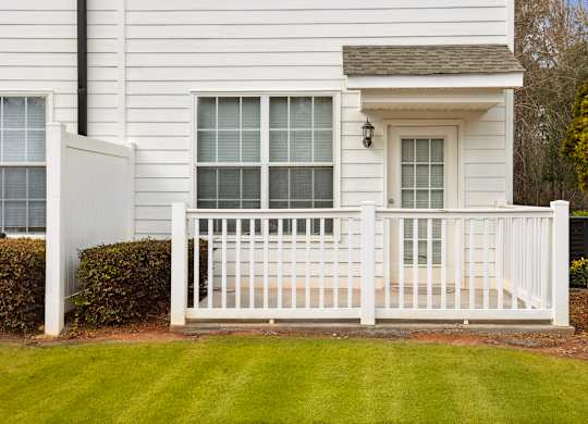 A white house with a white fence and a small window.