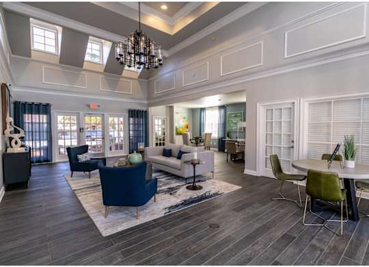 A spacious living room with a dark blue sofa and a chandelier.