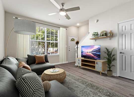 A living room with a grey couch and a television on a wooden stand.