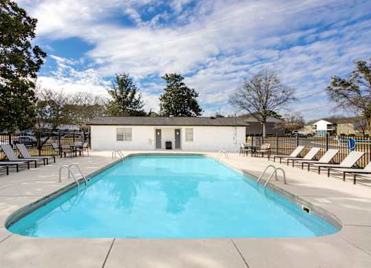 A large outdoor swimming pool with chaise lounges at Magnolia Apartments in Athens, Alabama