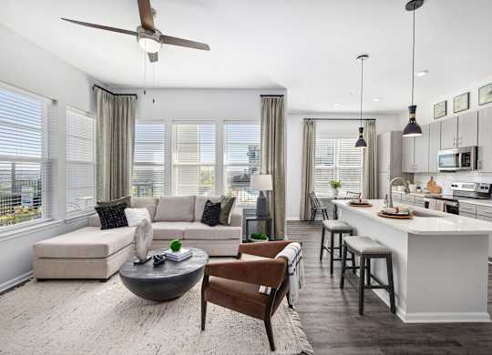 A modern kitchen and living room with a ceiling fan and a dining table.