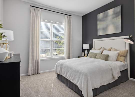A bedroom with a large bed and a window with curtains.