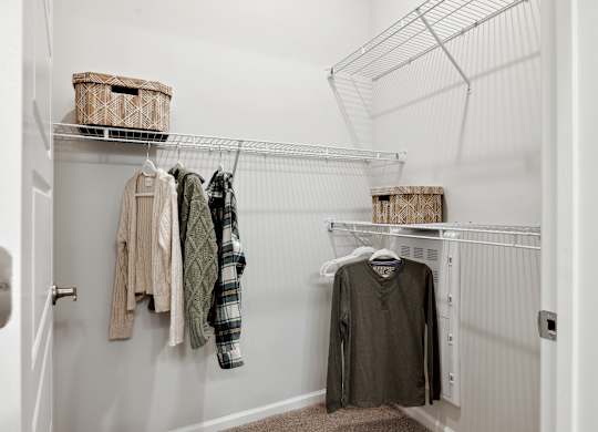 A white closet with clothes hanging on a wire rack.