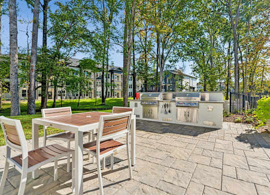 a patio with a table and chairs and a grill